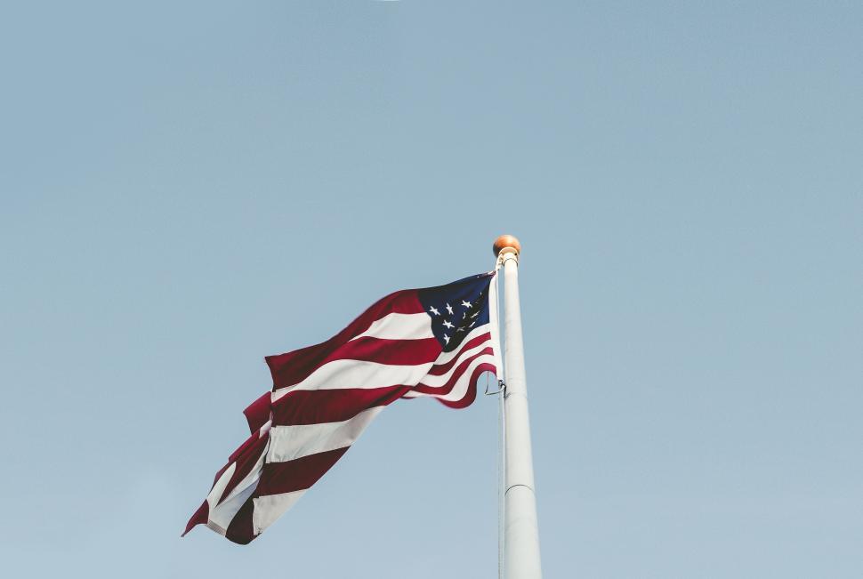 Free Image of American flag on pole against clear blue sky background. 