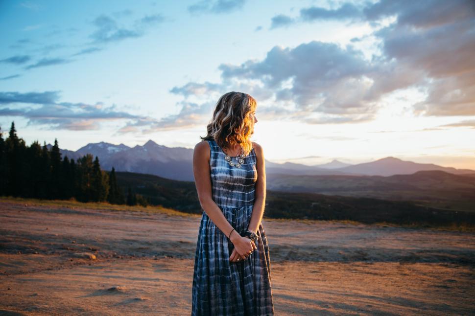 Free Image of Woman in dress standing on dirt road at sunset 