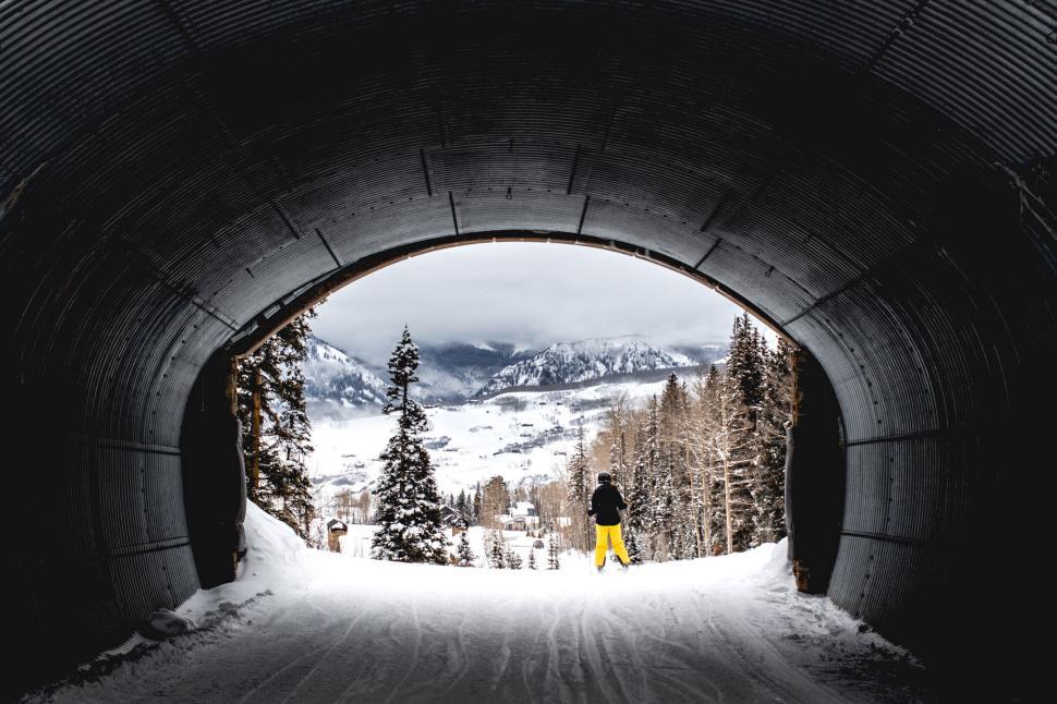 Free Image of Tunnel opening to snowy landscape with skier outside 