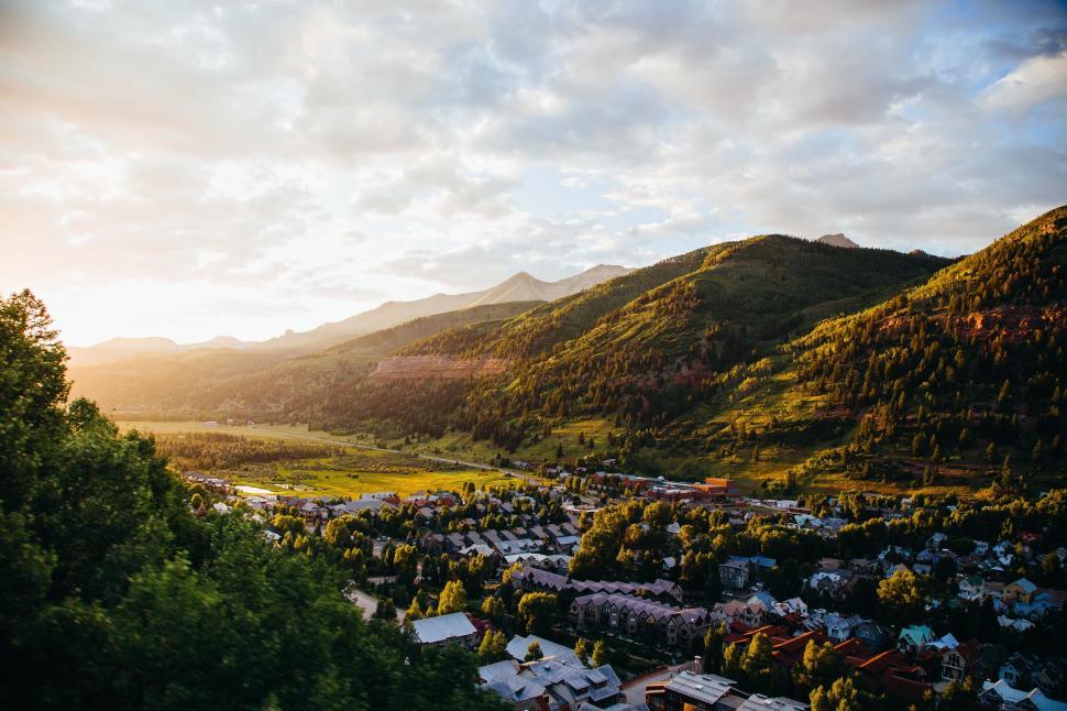 Free Image of Sunlit town nestled in lush green valley at sunrise. 