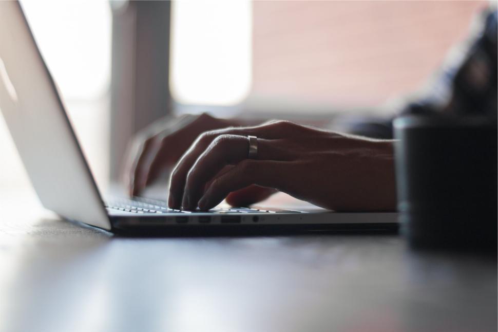 Free Image of Hands typing on a laptop in a dimly lit indoor setting. 