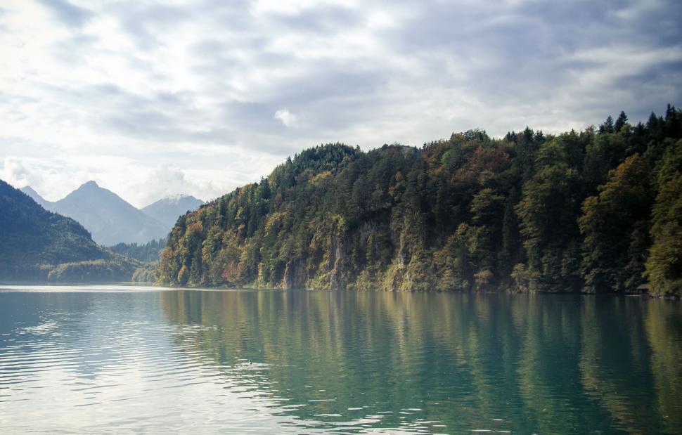 Free Image of Serene lake surrounded by forested hills and mountains. 