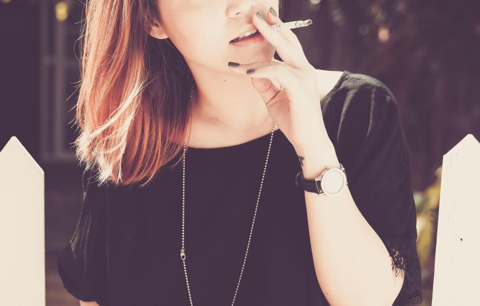 Free Image of Woman Smoking a Cigarette in a Relaxing Outdoor Setting 