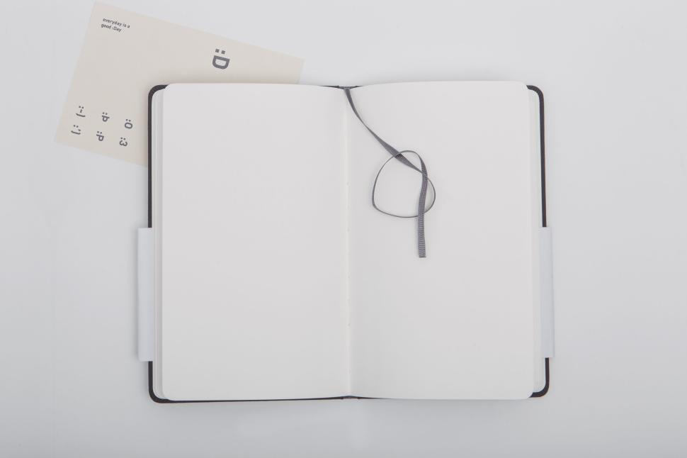 Free Image of Open blank notebook with ribbon marker on white surface 