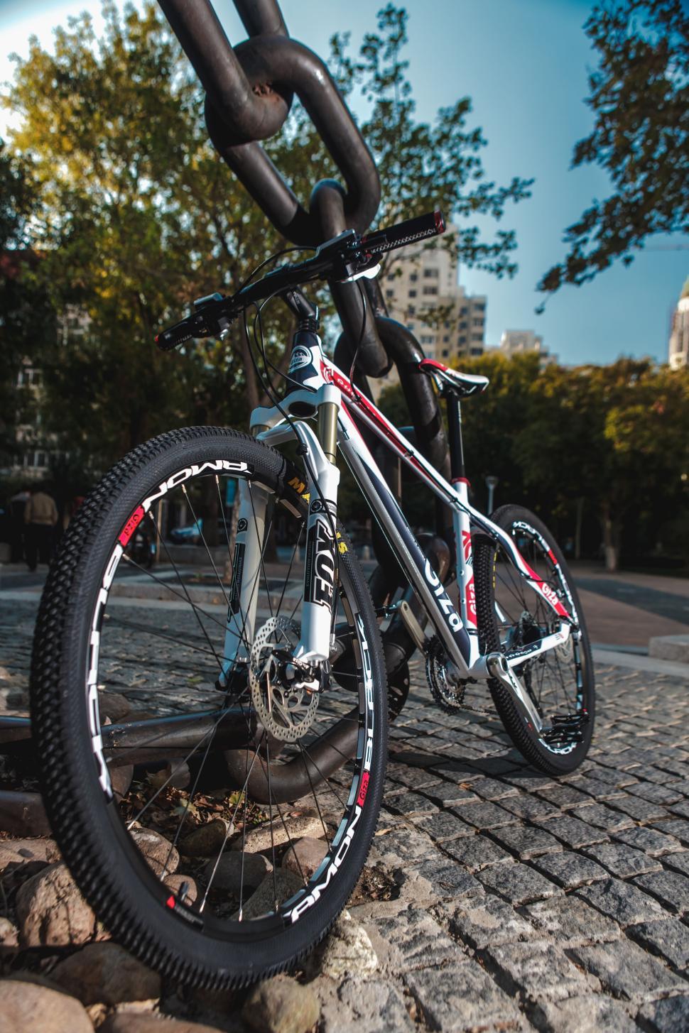 Free Image of Mountain bike parked under large metal chain outdoors. 