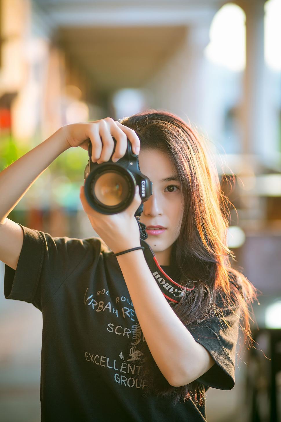 Free Image of Young woman with camera taking a photograph outdoors. 