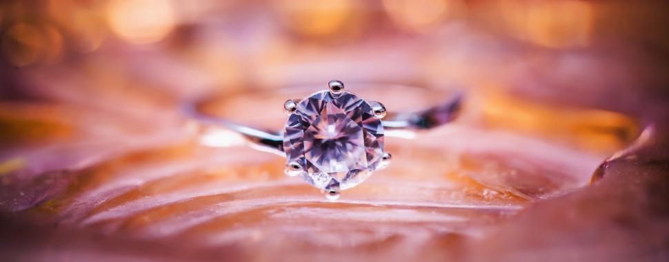 Free Image of A stunning diamond engagement ring on a reflective surface. 