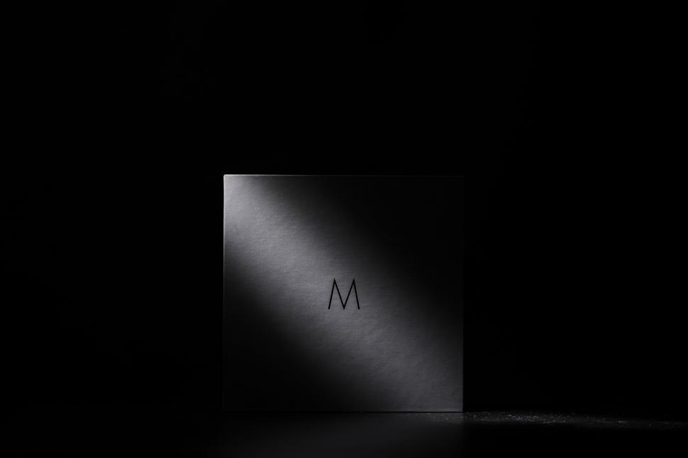 Free Image of Closed black packaging box with elegant letter M label. 