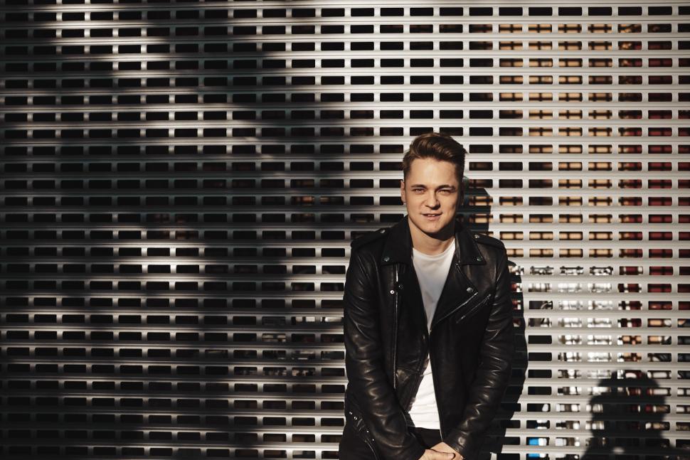 Free Image of People and lifestyle concept. Outdoor image of handsome cheerful young male with charismatic smile wearing stylish leather jacket posing isolated against grid copy space surface background 