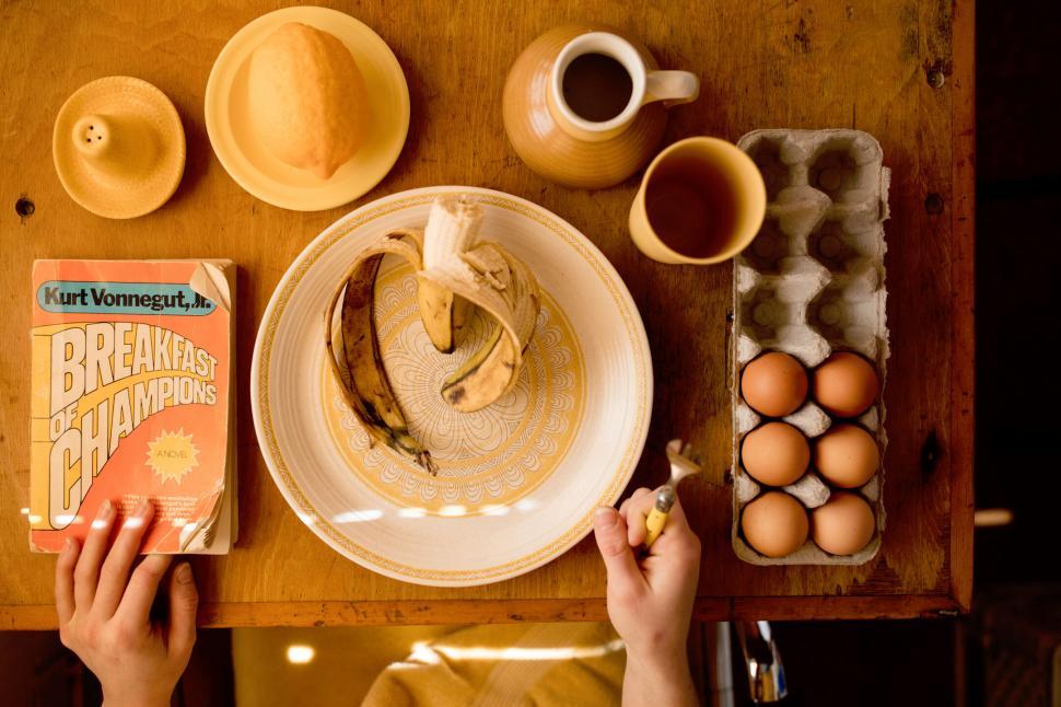Free Image of Breakfast table with book, bananas, eggs and pitcher. 