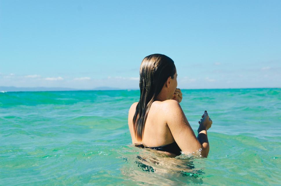 Free Image of Woman in black swimsuit swimming in crystal clear ocean 