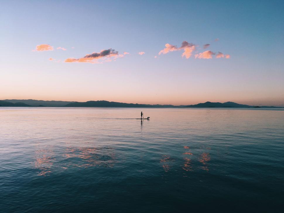 Free Image of Person paddleboarding on a calm lake at sunset. 