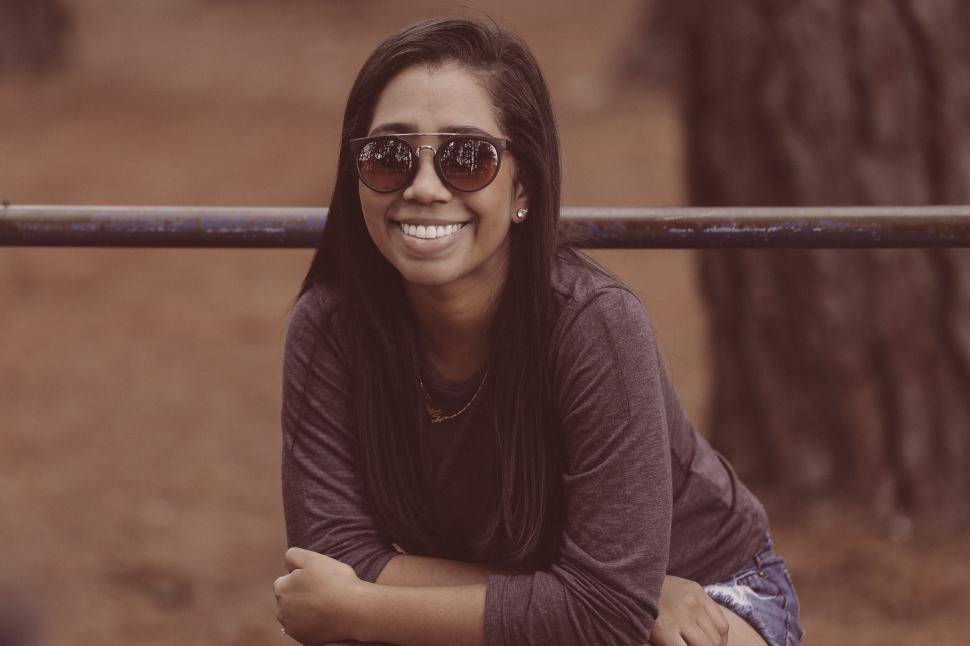 Free Image of Smiling woman with sunglasses in a park setting. 