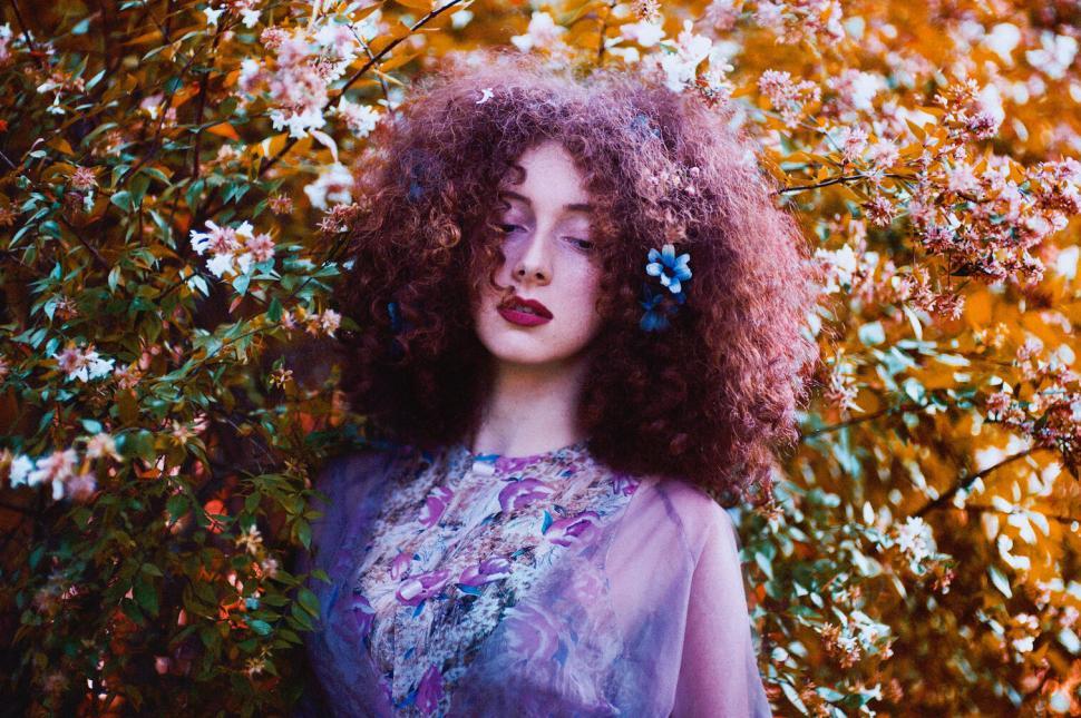 Free Image of Woman surrounded by flowers with her eyes closed softly. 