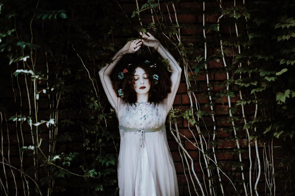 Free Image of Woman in white dress with flowers in her curly hair. 