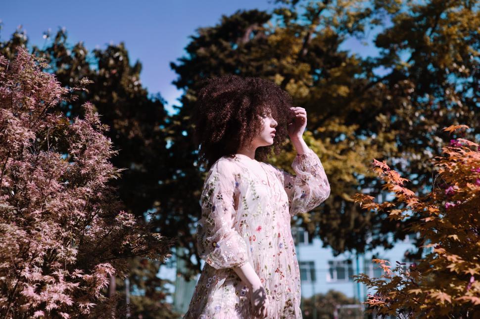 Free Image of Woman in floral dress standing in a park setting. 