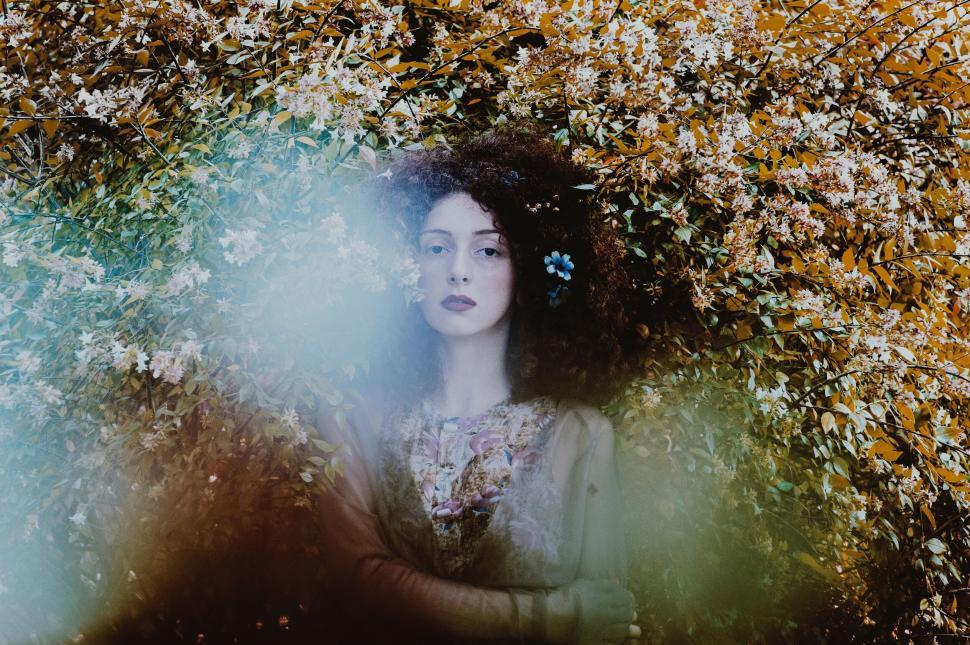 Free Image of Woman amidst flowers with dreamy, ethereal atmosphere. 