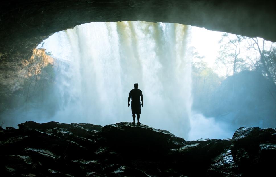 Free Image of Silhouette of a person in front of a majestic waterfall 