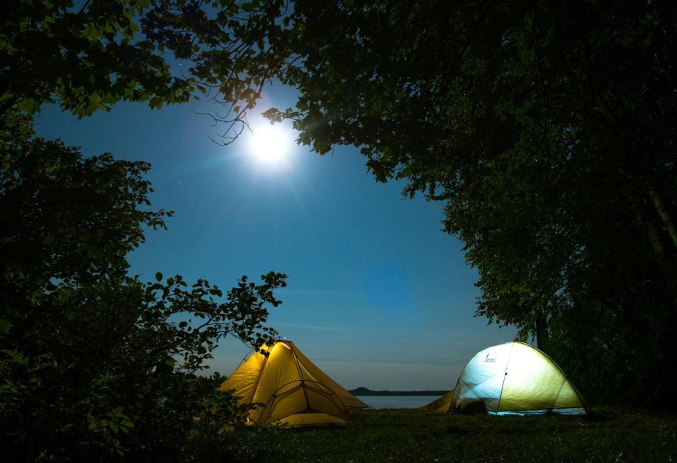 Free Image of Glowing tents under full moon in forest at night. 