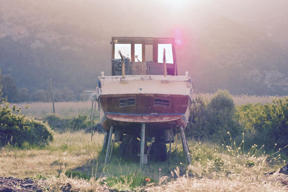 Free Image of Aged boat on dry land with mountains in background 