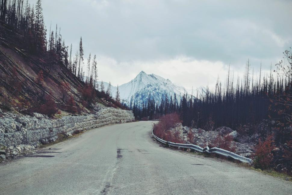 Free Image of Winding mountain road with snow-capped peaks in distance 