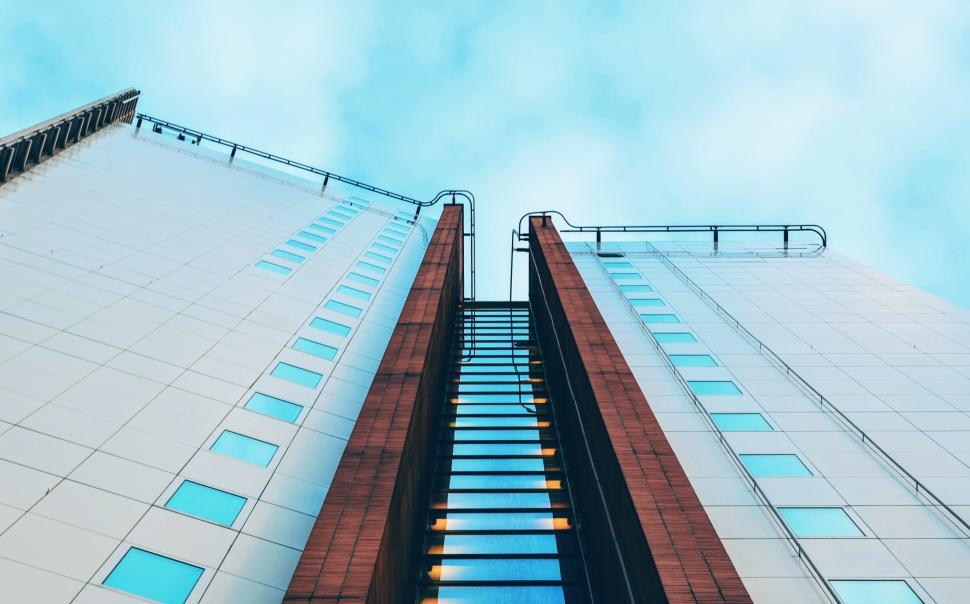Free Image of Symmetrical high-rise buildings with blue cloudy sky above. 