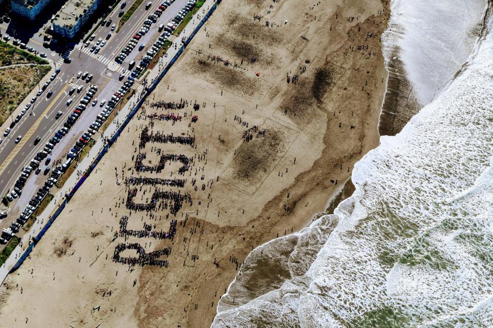 Free Image of Aerial view of beach with word RESIST formed by people 
