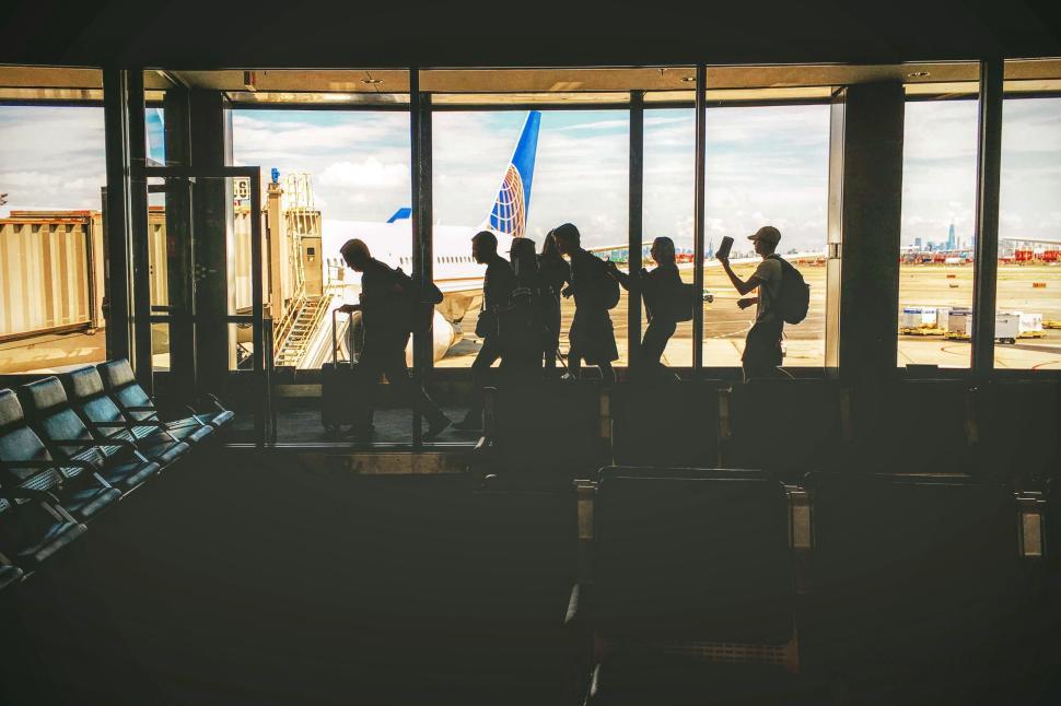 Free Image of Travelers silhouetted at airport terminal window 
