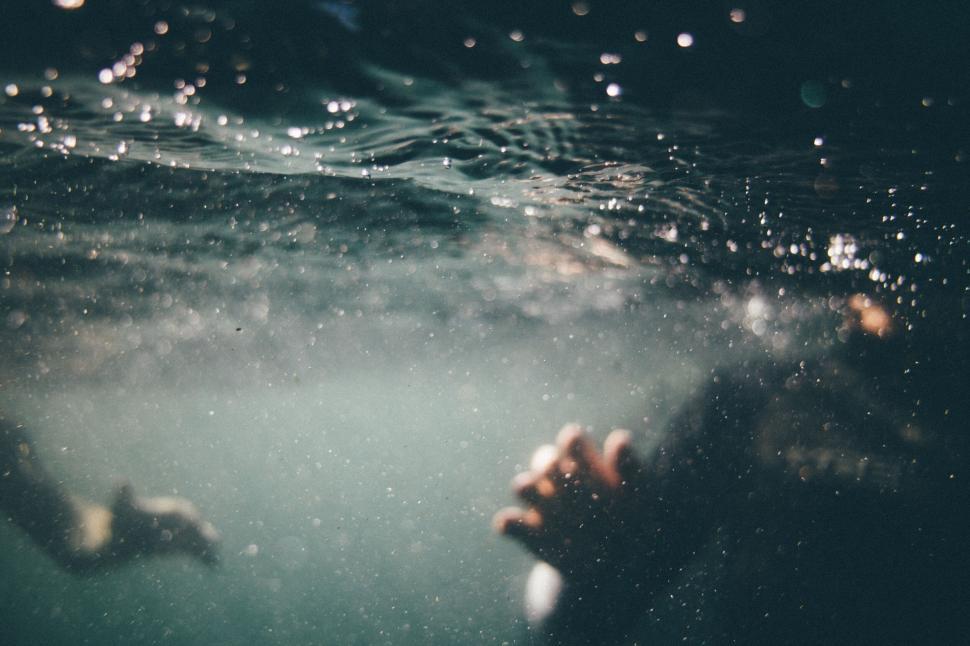 Free Image of Blurred underwater view with a swimmer in the distance 