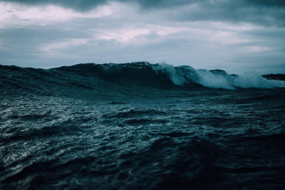 Free Image of Dramatic waves in the ocean with cloudy sky above 