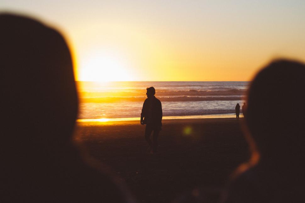 Free Image of Silhouette of person walking on beach at sunset time 
