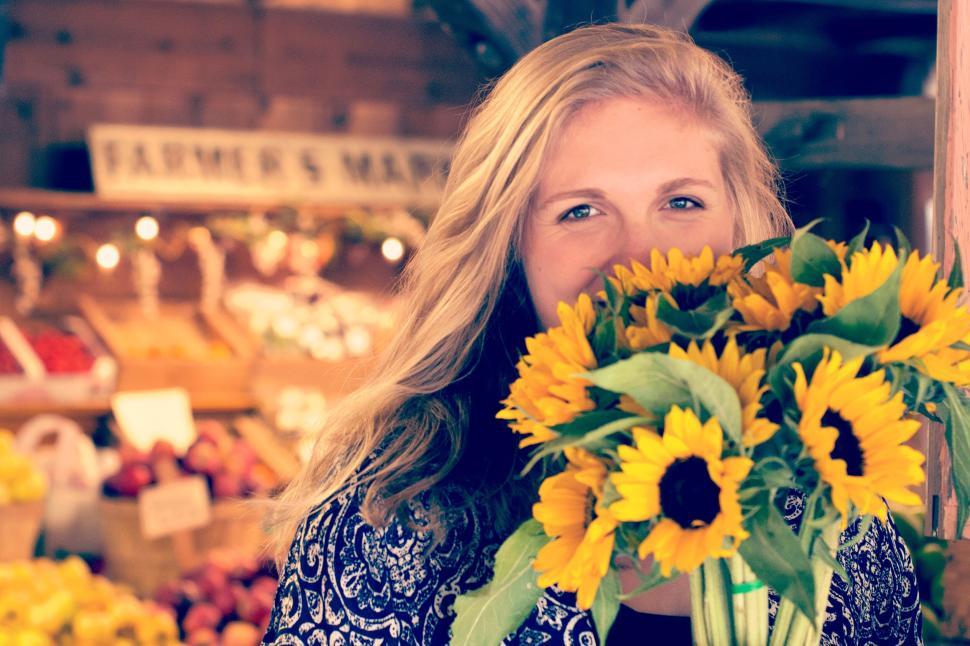 Free Image of Individual holding a bouquet of fresh sunflowers inside 