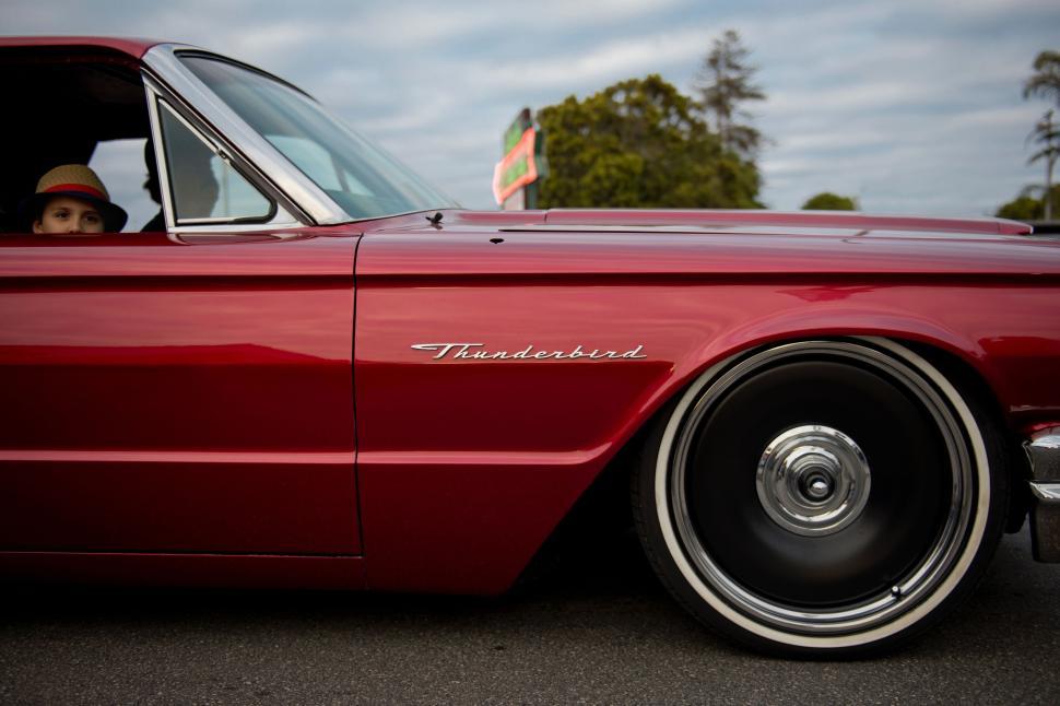 Free Image of Classic red Thunderbird with large chrome wheels parked 