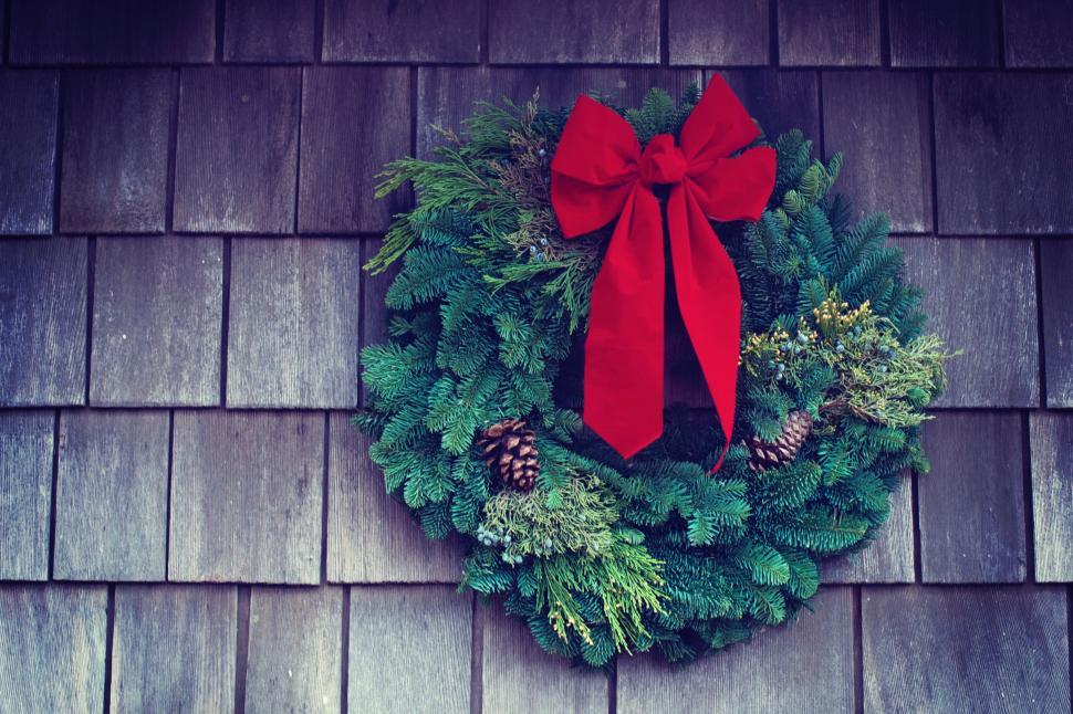 Free Image of Festive holiday wreath with red bow on wooden door 