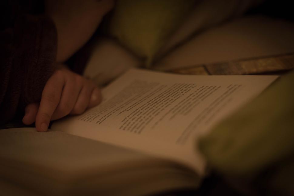 Free Image of Person reading a book in a dimly lit cozy setting 