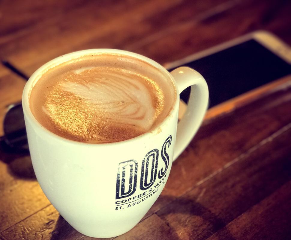 Free Image of Latte with intricate foam art in a branded coffee mug 