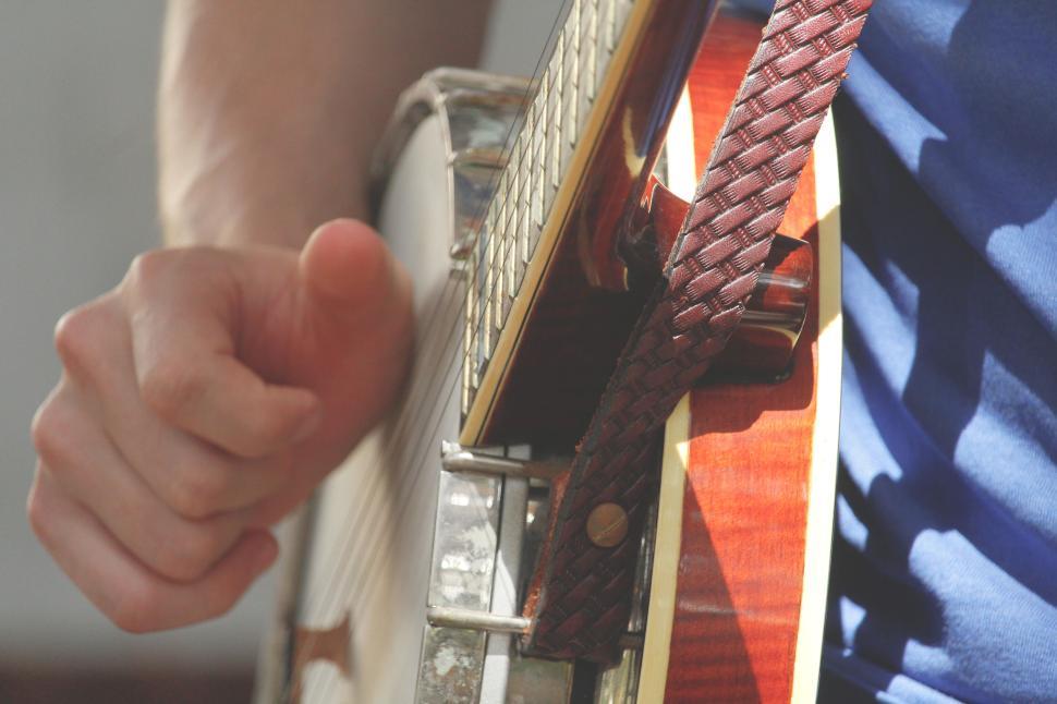 Free Image of Close-up of a person playing a banjo with a braided strap 