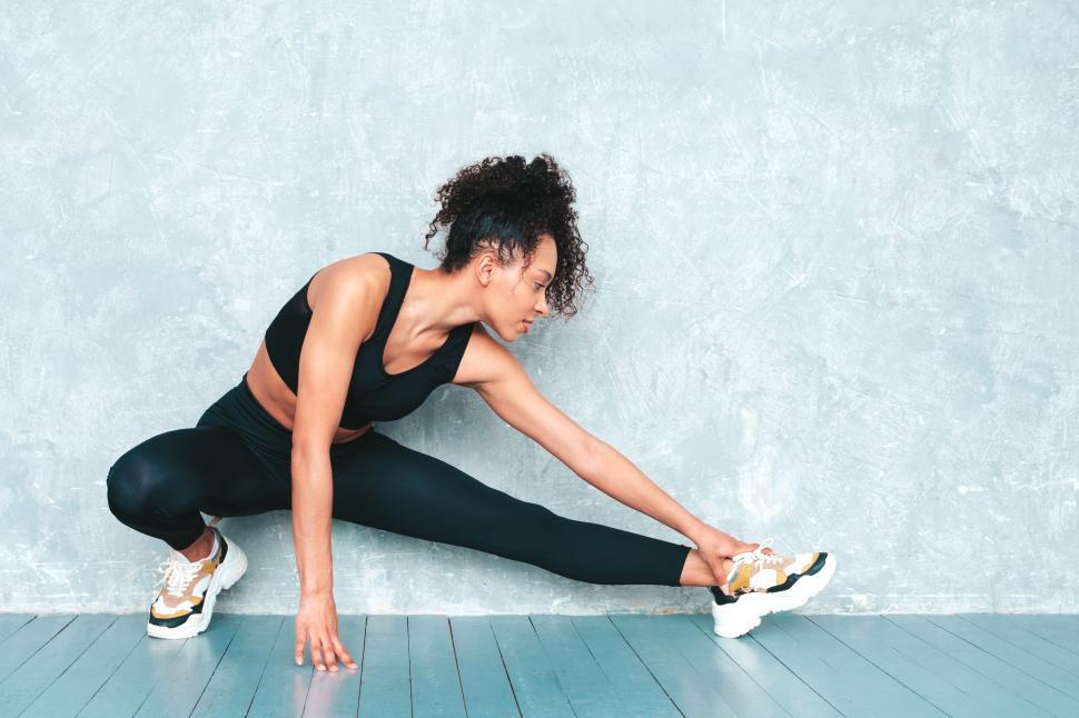 Free Image of Person stretching in black athletic wear and sneakers 