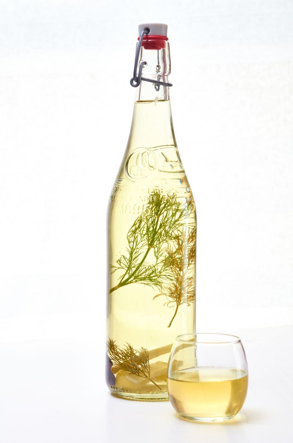 Free Image of Herbal infused bottle with small glass of drink. 