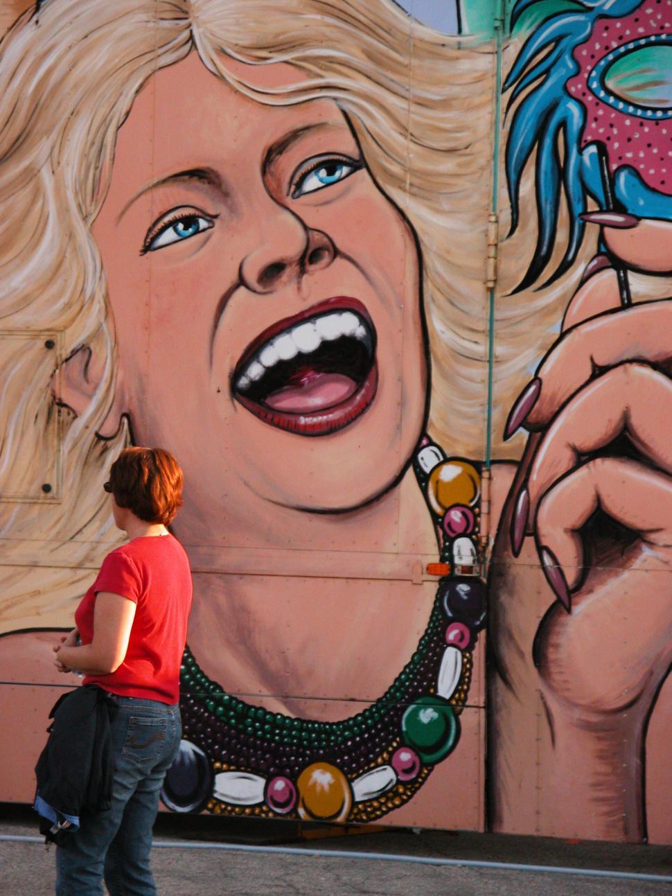 Free Image of Woman admiring large colorful mural with joy depicted 