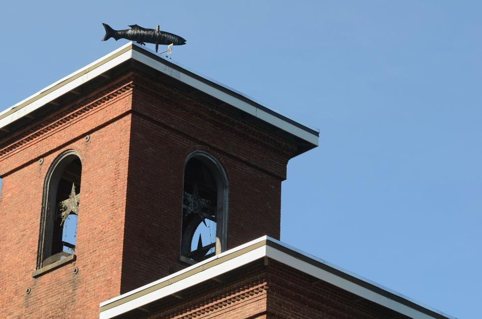 Free Image of Brick building with black fish statue on its rooftop 