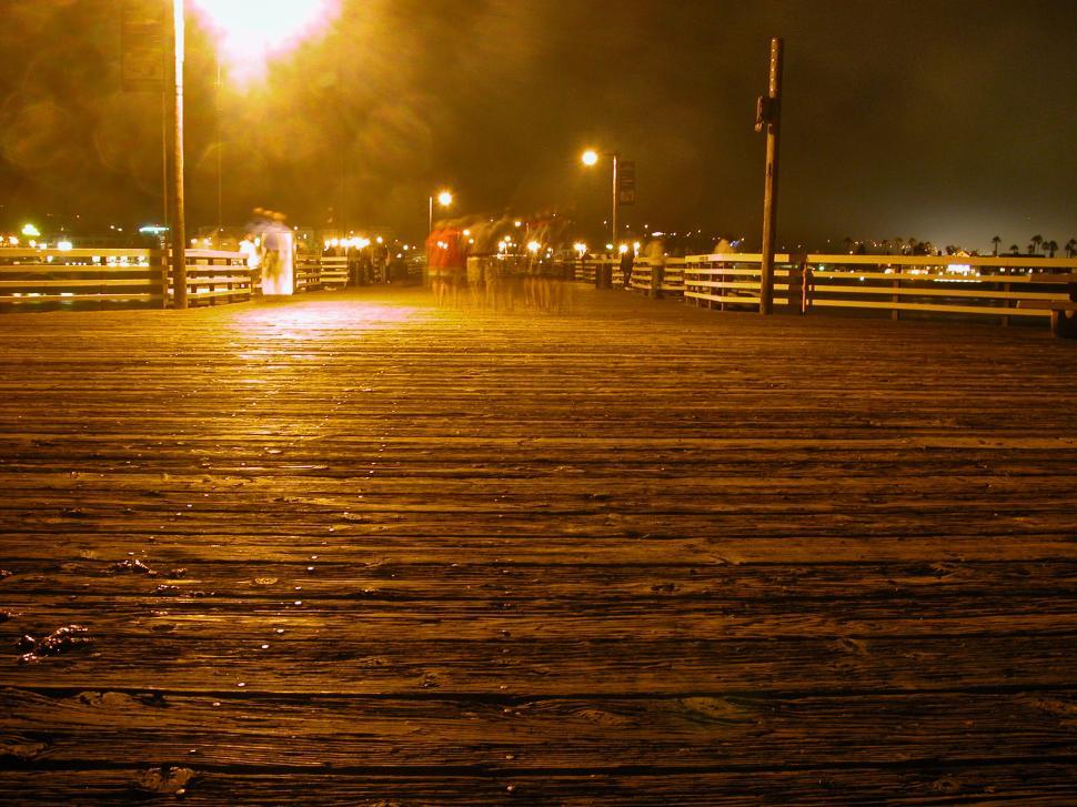Free Image of Dimly lit boardwalk at night with light reflections. 