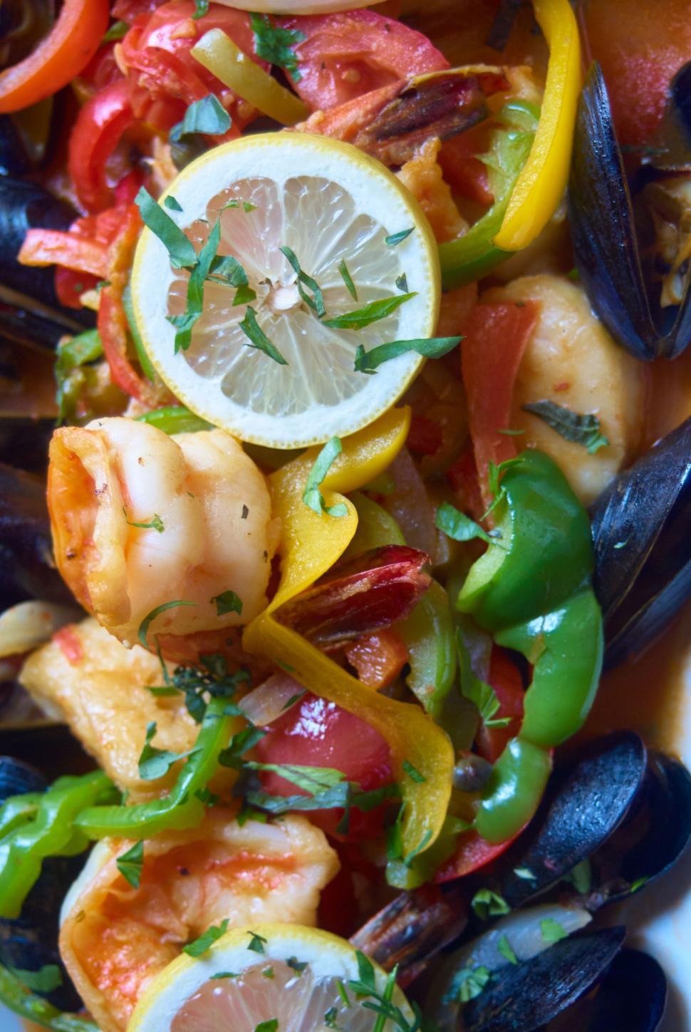 Free Image of Delicious seafood dish with lemon slices, peppers, and herbs 