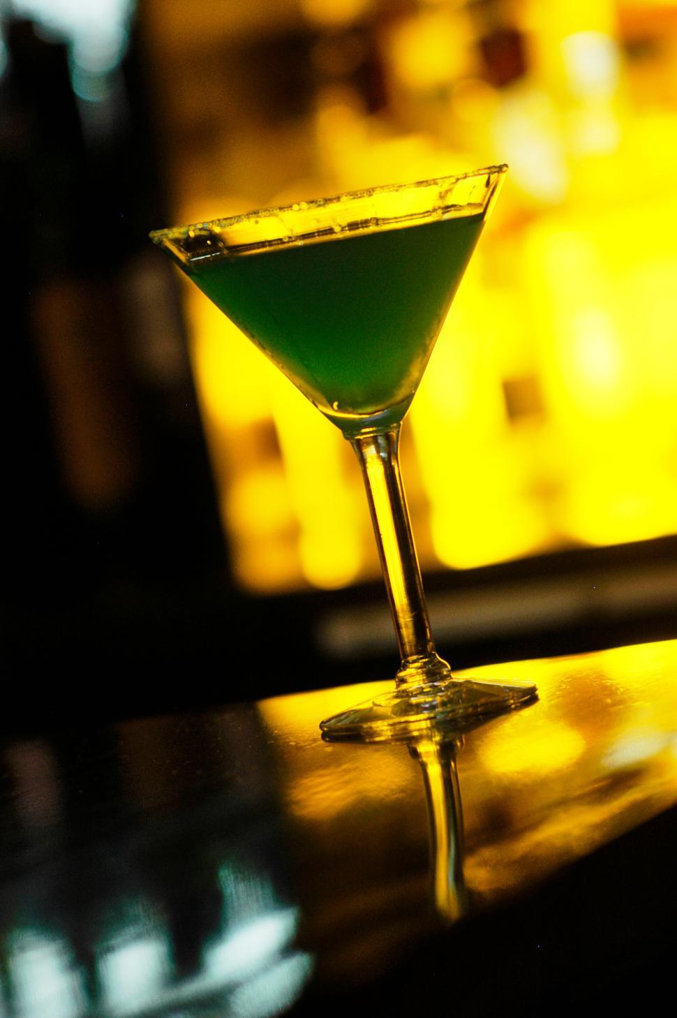 Free Image of Martini glass with green cocktail on a reflective surface 
