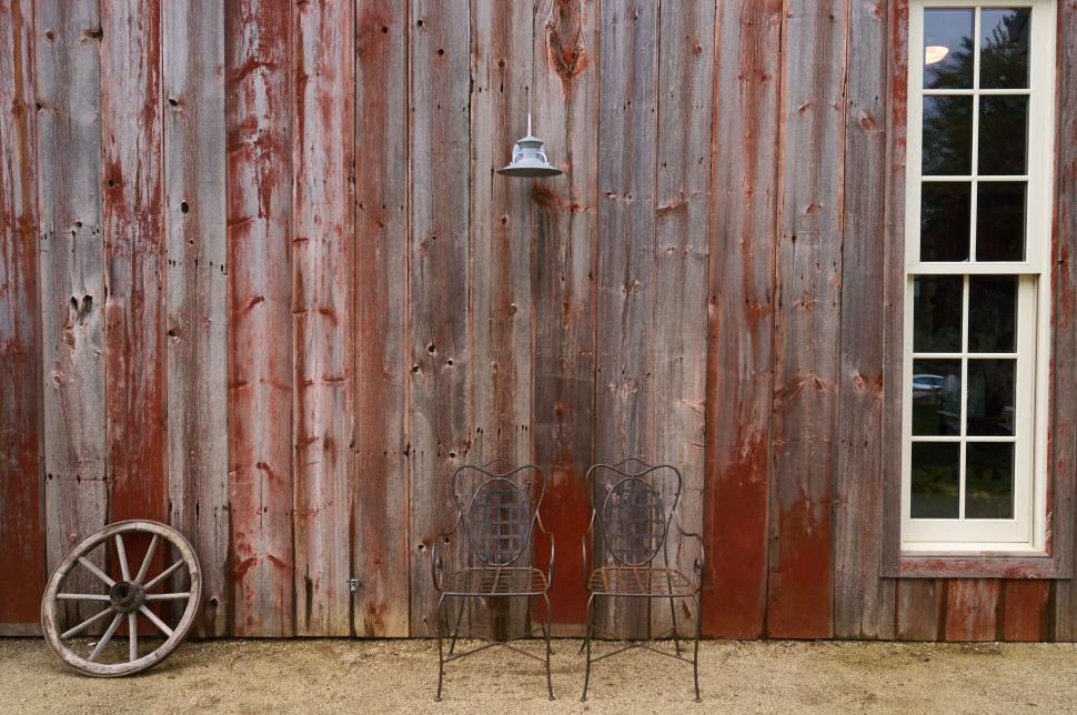 Free Image of Rustic scene with two chairs against a wooden barn wall 