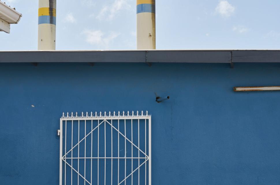 Free Image of Two yellow and blue industrial towers behind a metal gate 