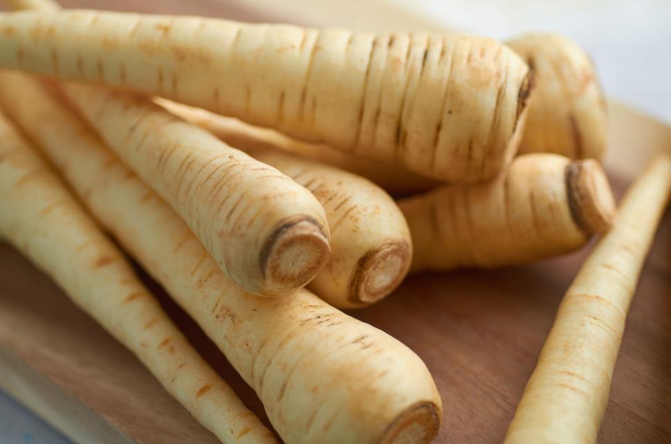 Free Image of Freshly harvested parsnips arranged on a wooden board. 