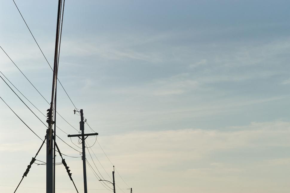Free Image of Series of utility poles with blue sky background 
