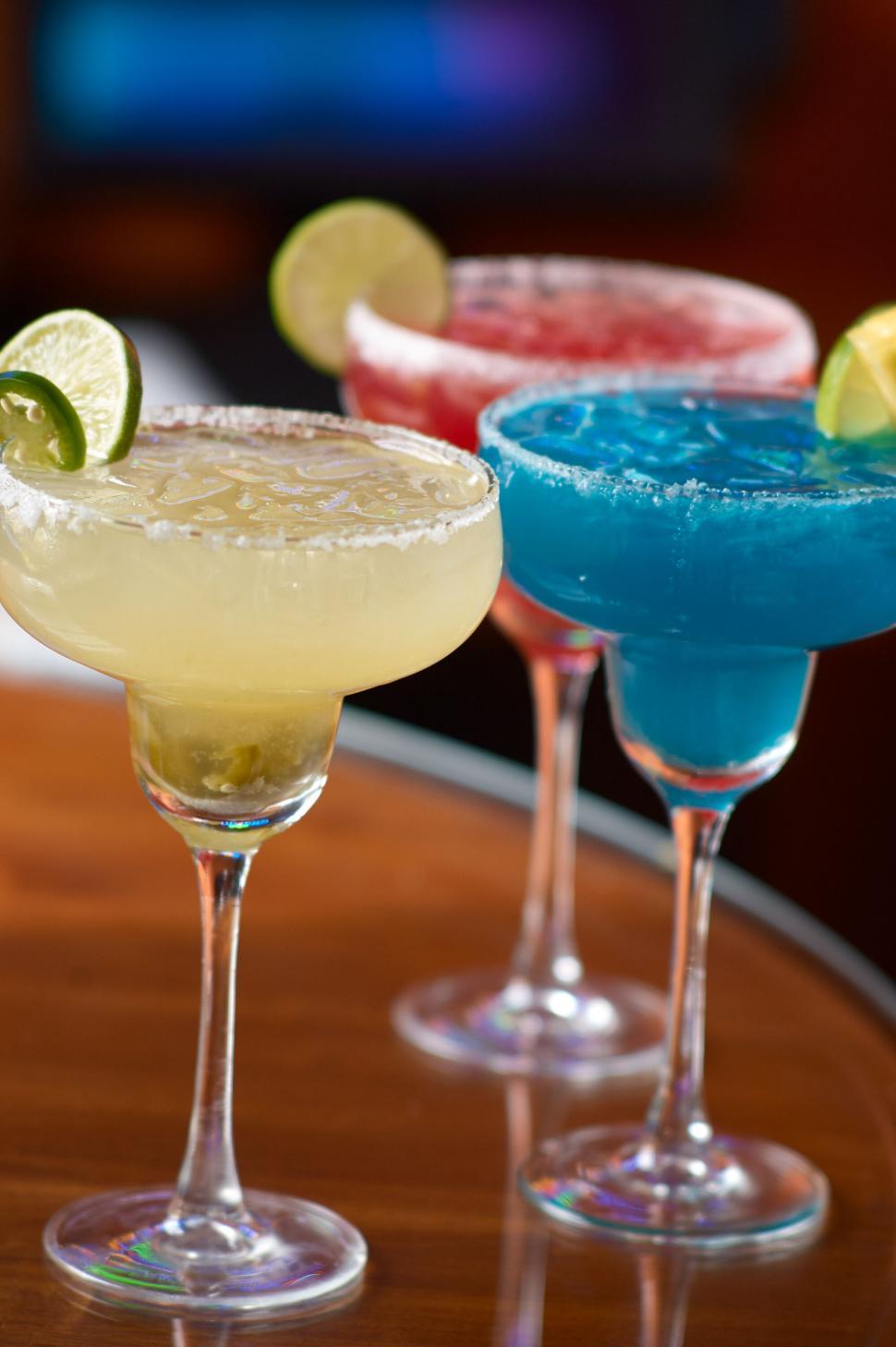 Free Image of Three colorful cocktails in glasses with lime garnishes 