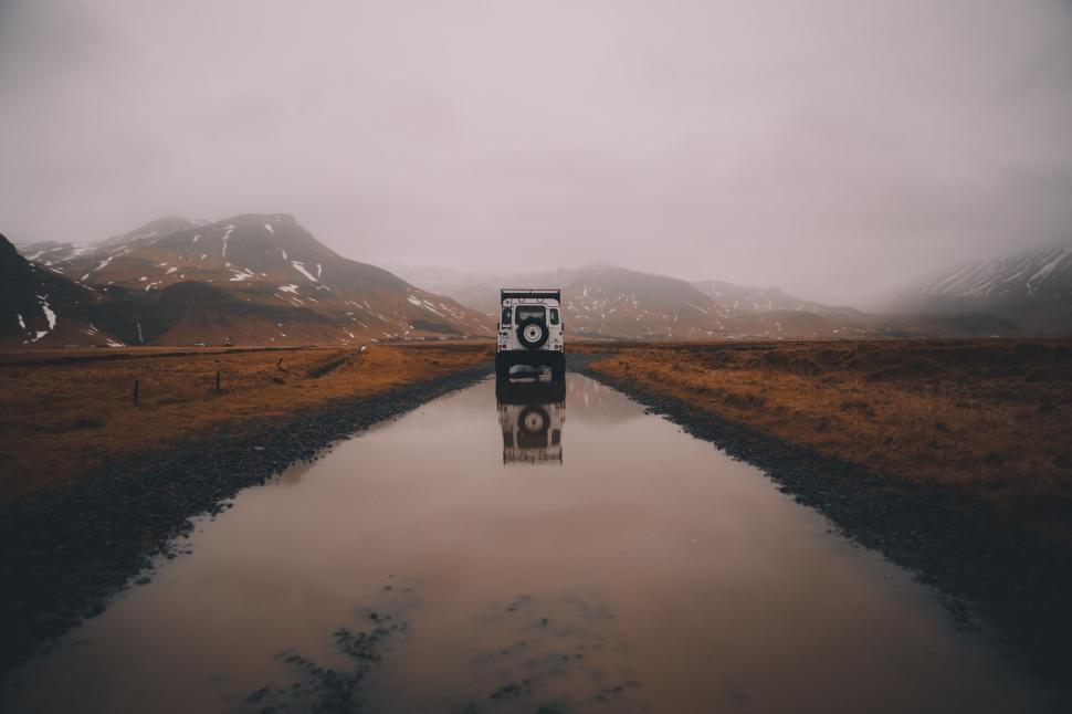Free Image of Off-road vehicle on a flooded road amidst remote hills. 